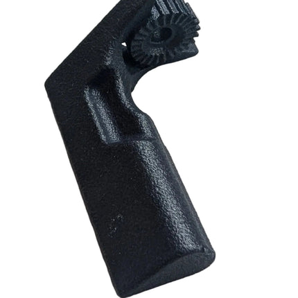 A small black molded plastic component with a textured, ribbed top surface, resting on a piece of white foam over a green cutting mat.