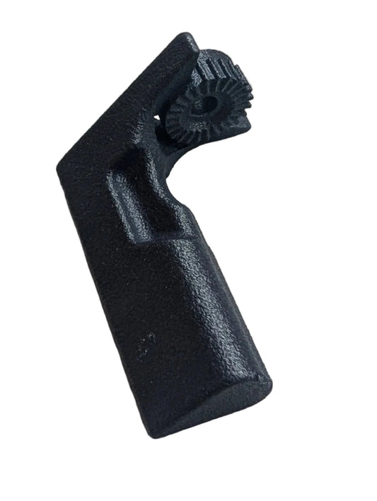 A small black molded plastic component with a textured, ribbed top surface, resting on a piece of white foam over a green cutting mat.